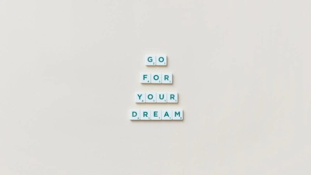 Inspirational text 'Go For Your Dream' made from Scrabble tiles on a plain background.